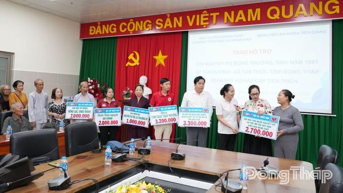 Chị Mộng Thường (bìa phải) nhận bảng tượng trưng tiền hỗ trợ của các nhà hảo tâm.