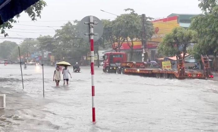 Xe cứu hộ và người dân đi bộ trên tuyến đường bị ngập úng.