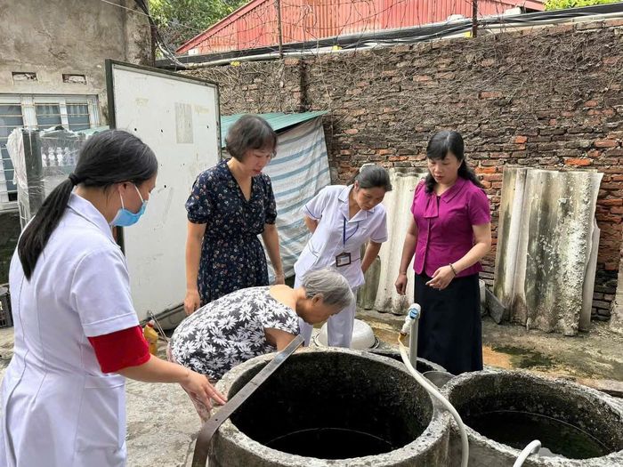 Đoàn kiểm tra của phường Bạch Mai hướng dẫn người dân tổng vệ sinh nhà ở, ngoại cảnh, các dụng cụ chứa nước và phát hiện, loại bỏ ổ bọ gậy, phòng tránh muỗi đốt... Ảnh: PV