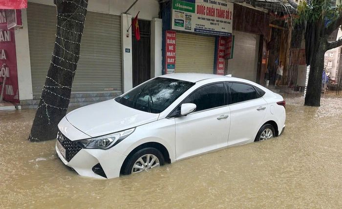 Một ô tô đỗ bên đường bị mắc kẹt giữa khu vực ngập nước. (Ảnh: Tâm Phạm)