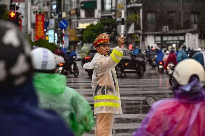 Bóng lưng vững chãi nhìn từ góc của một người đi xe máy. Giữa ngã tư ken đặc áo mưa, hiệu lệnh của cảnh sát giao thông đảm bảo giao thông thông suốt