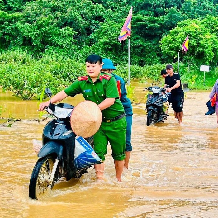 Công an xã Vân Du hỗ trợ người dân di chuyển qua các điểm tràn chưa bị ngập sâu sáng 21/8. Ảnh: CAVD