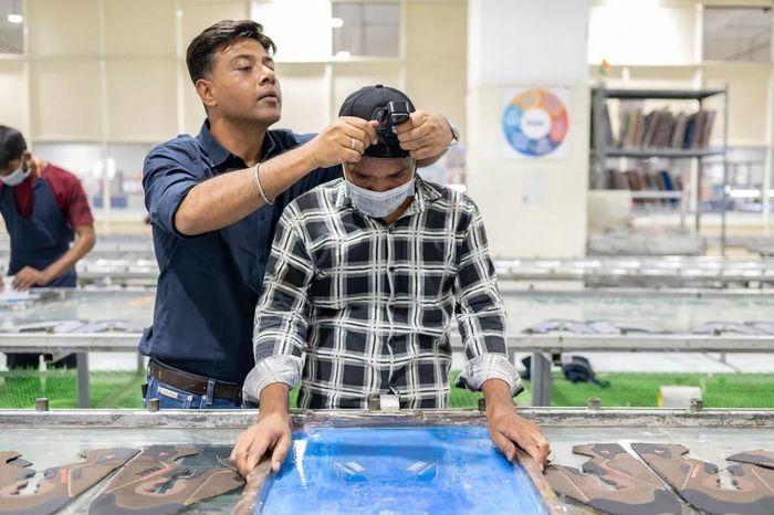  Avinash Pandey đang điều chỉnh máy ảnh gắn trên mũ của Jaswant Raikwar - người đang làm việc tại bộ phận in lụa của công ty Alpine Shoes ở ngoại ô Delhi. Ảnh: Saumya Khandelwal/Bloomberg. 