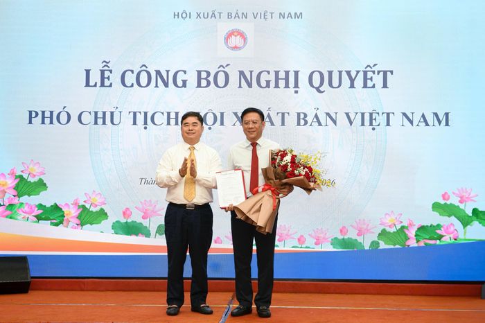 Chủ tịch Hội Xuất bản Việt Nam Phạm Minh Tuấn (bên trái) tặng hoa chúc mừng Phó chủ tịch Hội Xuất bản Việt Nam Nguyễn Ngọc Hồi.