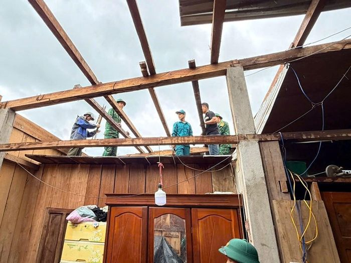 Bộ đội cùng chính quyền địa phương giúp dân lợp lại mái nhà