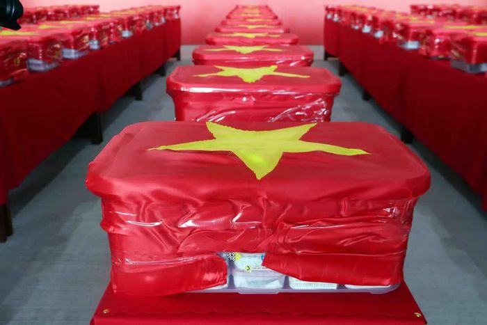 Các mẫu sinh phẩm hài cốt liệt sĩ được niêm phong, đóng gói nghiêm ngặt vào thùng chuyên dụng, phủ Quốc kỳ trước khi đưa lên máy bay. Ảnh: Xuân Khu - TTXVN