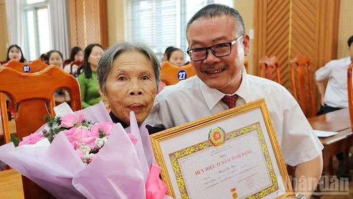 Bí thư Đảng ủy xã Sơn Cẩm Hà Trầm Quế Hương trao tặng Huy hiệu Đảng cho đảng viên 55 năm tuổi Đảng.