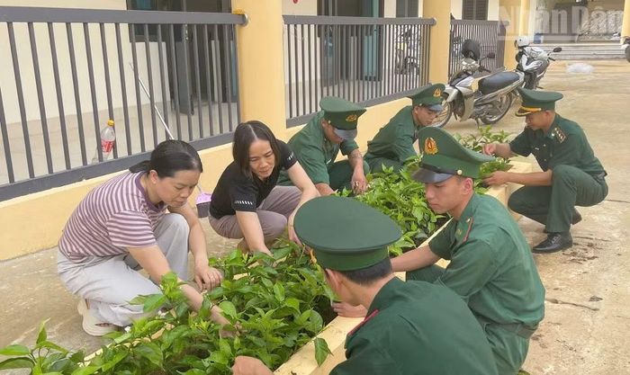 Cán bộ, chiến sĩ Đồn Biên phòng Chiềng On và giáo viên chăm sóc vườn hoa, cây cảnh tại khuôn viên Trường phổ thông nội trú tiểu học và trung học cơ sở xã Yên Sơn. (Ảnh: QUÀNG HÙNG)