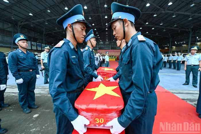 Nghi thức trang trọng chuyển mẫu hài cốt liệt sĩ từ máy bay xuống tại Sân bay Gia Lâm để làm lễ dâng hương tưởng niệm.