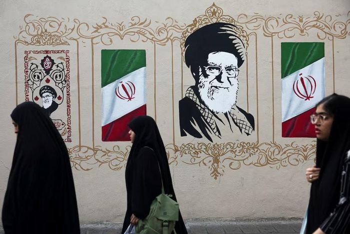 Người dân đi ngang qua bức tường có ảnh lãnh tụ tối cao Iran Ayatollah Ali Khamenei trên một con phố ở Tehran (Iran), ngày 13-8. Ảnh: Reuters
