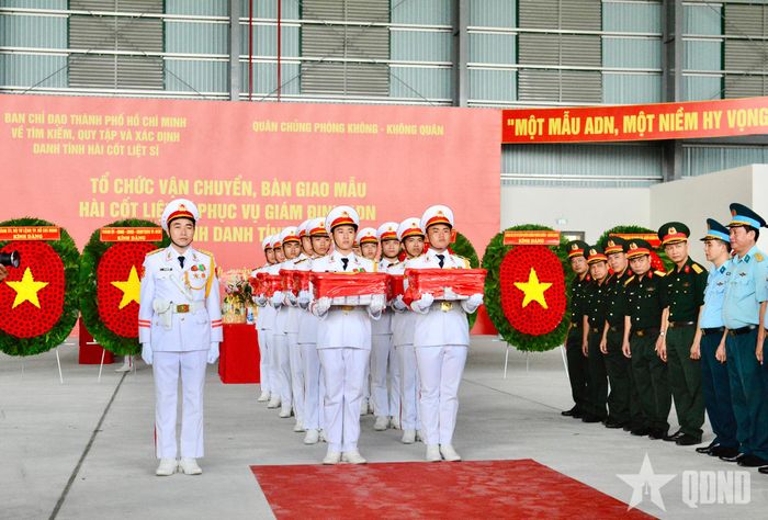 Lực lượng làm nhiệm vụ thực hiện nghi thức di chuyển các thùng đựng mẫu sinh phẩm hài cốt liệt sĩ ra máy bay.