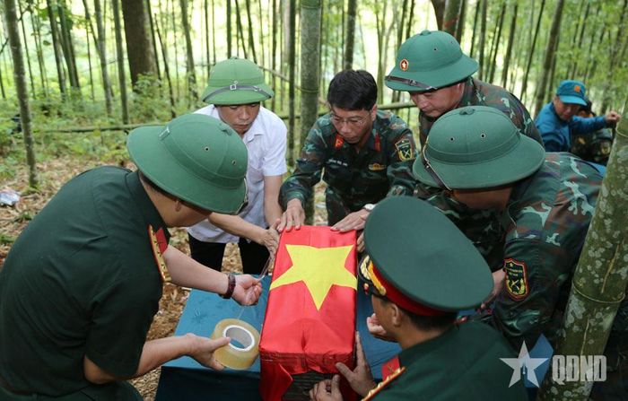 Thực hiện nghi lễ phủ Quốc kỳ và đưa hài cốt liệt sĩ rời khu vực khai quật. 