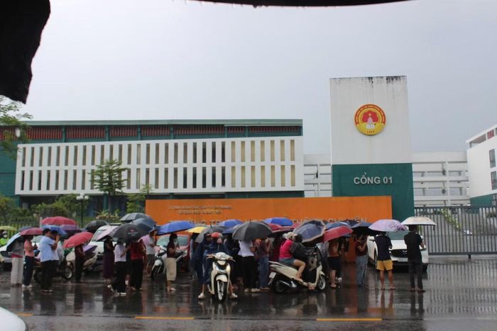Phụ huynh đội mưa đón con em trong kỳ thi lại tại Trường THPT chuyên Tuyên Quang.