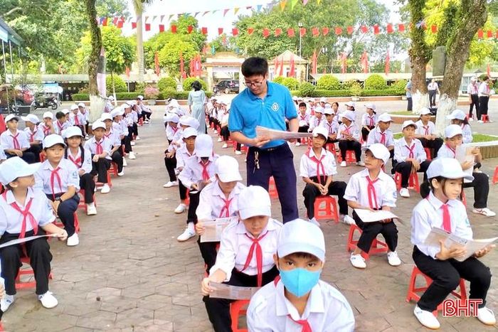 Cán bộ BHXH phát tờ rơi và tuyên truyền về chính sách BHYT cho học sinh.