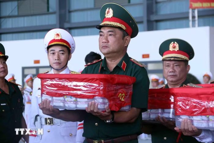 Trung tướng Lê Xuân Thế, Tư lệnh Quân khu 7 kính cẩn chuyển mẫu sinh phẩm hài cốt liệt sỹ lên máy bay vận chuyển ra Hà Nội để phục vụ công tác xét nghiệm ADN xác định danh tính liệt sỹ. (Ảnh: Xuân Khu/TTXVN)