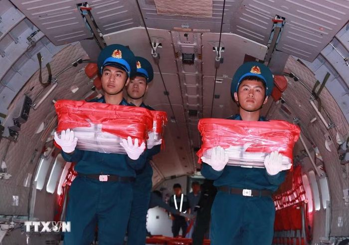 Nghi thức trang trọng chuyển mẫu hài cốt liệt sỹ từ máy bay xuống tại Sân bay Gia Lâm để làm lễ dâng hương tưởng niệm. (Ảnh: Trọng Đức/TTXVN)
