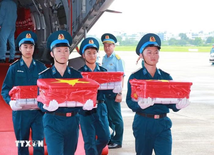 Nghi thức trang trọng chuyển mẫu hài cốt liệt sỹ từ máy bay xuống tại Sân bay Gia Lâm để làm lễ dâng hương tưởng niệm. (Ảnh: Trọng Đức/TTXVN)