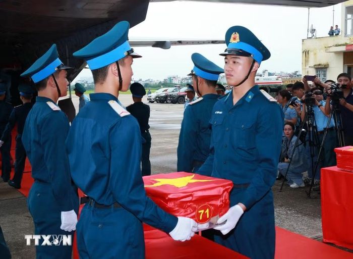 Nghi thức trang trọng chuyển mẫu hài cốt liệt sỹ từ máy bay xuống tại Sân bay Gia Lâm để làm lễ dâng hương tưởng niệm. (Ảnh: Trọng Đức/TTXVN)