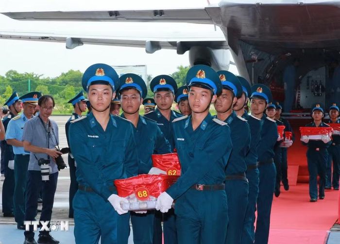 Nghi thức trang trọng chuyển mẫu hài cốt liệt sỹ từ máy bay xuống tại Sân bay Gia Lâm để làm lễ dâng hương tưởng niệm. (Ảnh: Trọng Đức/TTXVN)