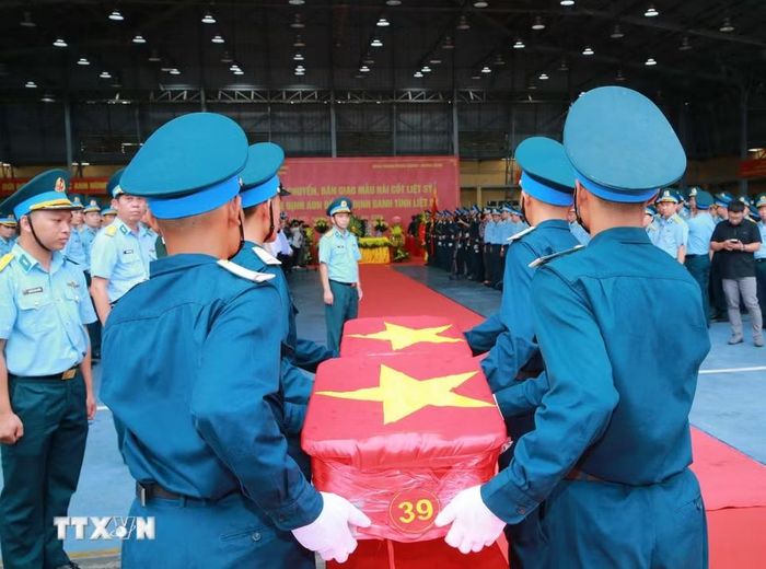 Nghi thức trang trọng chuyển mẫu hài cốt liệt sỹ từ máy bay xuống tại Sân bay Gia Lâm để làm lễ dâng hương tưởng niệm. (Ảnh: Trọng Đức/TTXVN)
