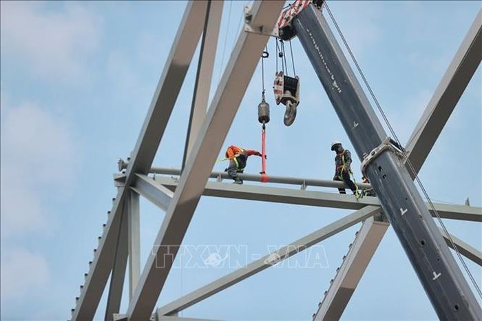 Tại công trường, các nhà thầu đang huy động hệ thống cần cẩu và tập kết các cấu kiện để chuẩn bị lắp dựng mái vòm thép có tổng trọng lượng khoảng 8.500 tấn.