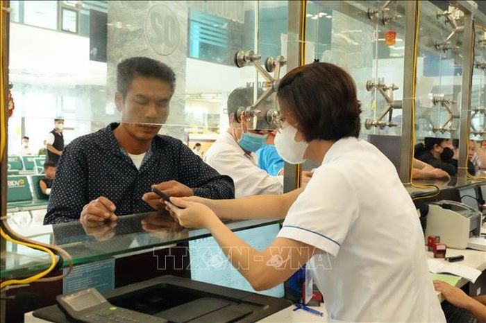 Cán bộ y tế Bệnh viện Đa khoa Nam Định hướng dẫn người dân sử dụng ứng dụng VNeID trong đăng ký khám, chữa bệnh.