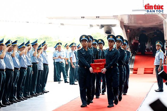 Cán bộ, chiến sĩ Quân chủng Phòng không - Không quân trang nghiêm đưa các thùng chứa mẫu sinh phẩm hài cốt liệt sĩ xuống máy bay.