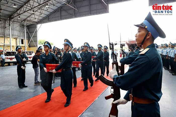 Các thùng chứa mẫu sinh phẩm hài cốt liệt sĩ được đưa khỏi máy bay trong sự thành kính của cán bộ, chiến sĩ tham dự lễ đón.