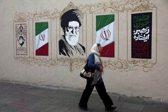 Một người phụ nữ đi ngang qua bức tranh tường mô tả cố lãnh đạo tối cao của Iran, Ayatollah Ali Khamenei, trên một con phố ở Tehran, Iran, ngày 13/8. Ảnh: Reuters.