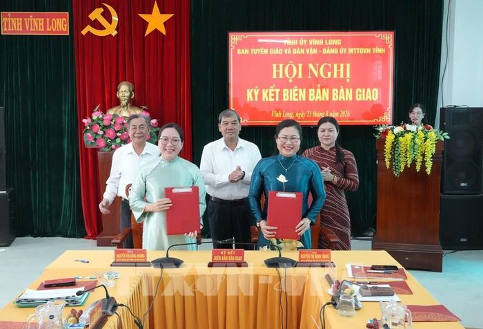 Lãnh đạo Ban Tuyên giáo và Dân vận Tỉnh ủy Vĩnh Long và Đảng ủy Mặt trận Tổ quốc Việt Nam tỉnh Vĩnh Long ký kết biên bản bàn giao. Ảnh: Phạm Minh Tuấn-TTXVN