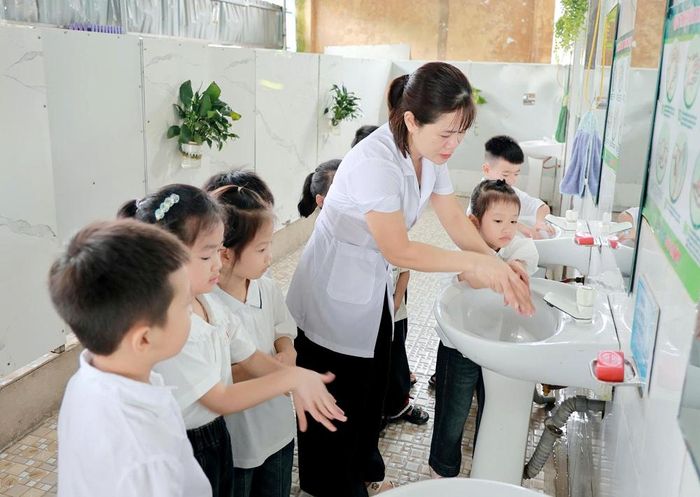  Nhân viên y tế Trường Tiểu học An Châu (xã Sơn Động) hướng dẫn học sinh lớp 1 làm quen với khu vực vệ sinh của nhà trường. 
