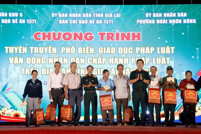  Đại tá Võ Tấn Tài (thứ 4 từ phải sang) trao quà cho người dân có hoàn cảnh khó khăn trong chương trình tuyên truyền pháp luật tại phường Hoài Nhơn Đông. Ảnh: H.P 