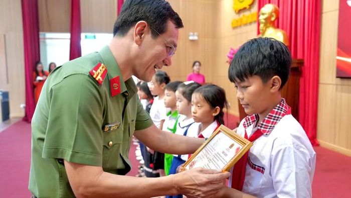Đại tá Ngô Cự Vinh - Phó Giám đốc Công an tỉnh Gia Lai trao thưởng cho các em là con đỡ đầu có thành tích xuất sắc trong học tập. Ảnh: Q.H