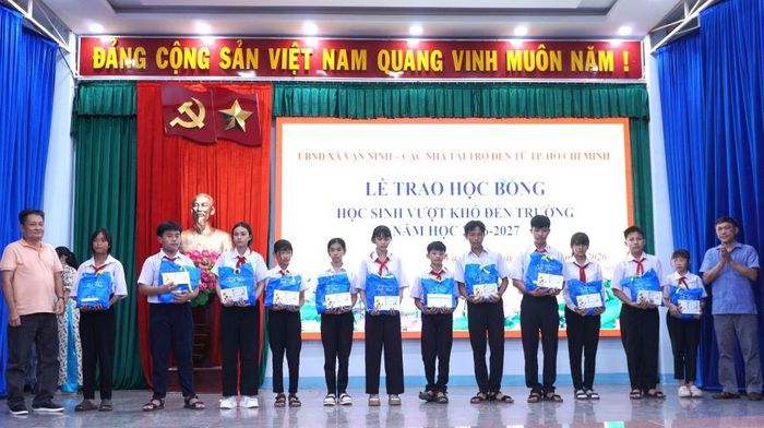 Lãnh đạo xã Vạn Ninh và nhà tài trợ trao học bổng và quà cho các học sinh.