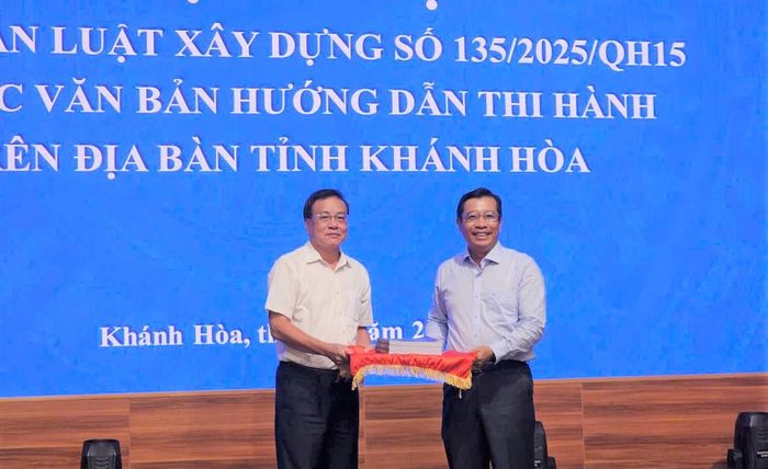 Ông Đàm Đức Biên, Phó cục trưởng Cục Kinh tế - Quản lý đầu tư xây dựng trao tài liệu tập huấn cho ông Nguyễn Thành Phú, Giám đốc Sở Xây dựng tỉnh Khánh Hòa.