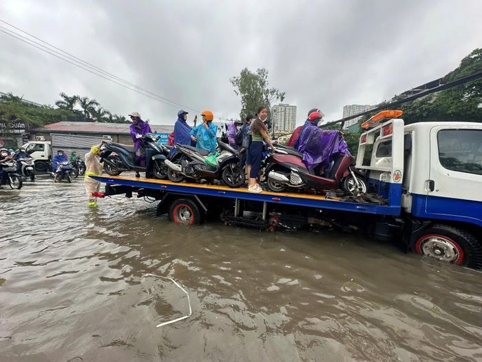 Lực lượng chức năng hỗ trợ người dân Thủ đô di chuyển qua khu vực úng ngập. Ảnh: Phạm Công