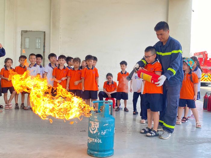 Học sinh được hướng dẫn sử dụng thao tác sử dụng bình chữa cháy dập tắt đám cháy. Ảnh: Phùng Trung