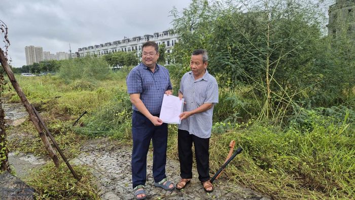 Đại diện Phòng Kinh tế xã Hoài Đức trao giấy chứng nhận quyền sử dụng đất tại khu đất tái định cư X1 cho các hộ dân, ngày 21-8. Ảnh: Hậu Lộc.