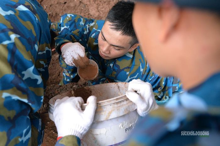 Một chiến sĩ múc nước, xử lý bùn đất trong quá trình khai quật. Ảnh: Tuấn Anh