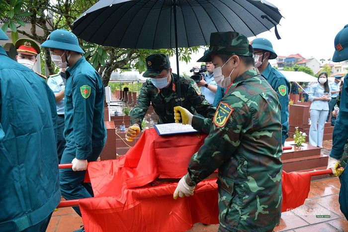 Cán bộ, chiến sĩ cẩn trọng di chuyển hài cốt liệt sĩ khỏi khu vực khai quật. Ảnh: Tuấn Anh
