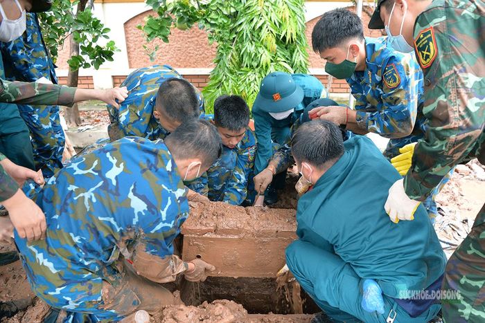Các lực lượng phối hợp đưa tiểu từ phần mộ lên mặt đất. Ảnh: Tuấn Anh