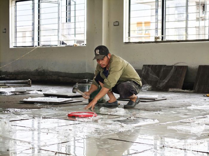 Bên trong, một công nhân đang lát nền.