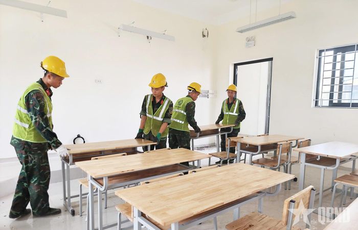 Bộ đội kê bàn ghế trong một phòng học.