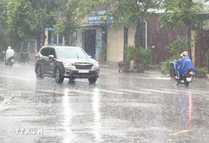 Người dân đi lại trong mưa lớn. Ảnh: TTXVN
