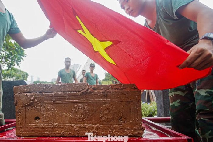 Khoảnh khắc tiểu quách được đưa lên mặt đất, các chiến sĩ nhẹ nhàng phủ lá Quốc kỳ lên trên. Giữa công trường khai quật, nghi thức giản dị tạo nên hình ảnh xúc động và trang nghiêm.