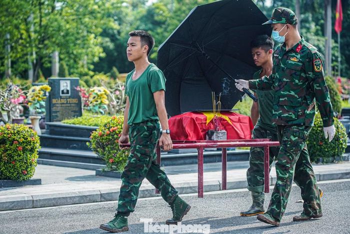 Các chiến sĩ che ô khi đưa hài cốt tới khu vực lấy mẫu giám định ADN. Lực lượng lấy mẫu được chia thành hai tổ, mỗi tổ 5 thành viên với nhiệm vụ cụ thể từ lấy mẫu, ghi hồ sơ đến vệ sinh, khử khuẩn dụng cụ.