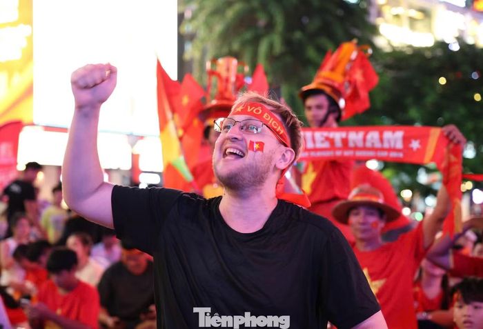 Dòng người đổ về mỗi lúc một đông, mang theo vô số cờ Tổ quốc, áo đội tuyển và băng rôn rợp trời, biến nơi đây thành một biển đỏ cuồng nhiệt. Du khách nước ngoài cũng cùng nhiệt cổ vũ cho đội tuyển Việt Nam.