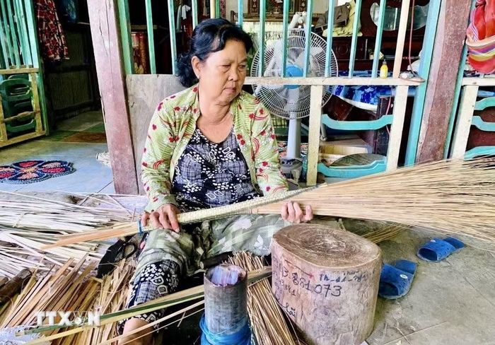 Người dân ấp Đông An, xã Phú Hòa, tỉnh An Giang tận dụng sân nhà, mái hiên để làm chổi cọng dừa. (Ảnh: Thanh Sang/TTXVN)
