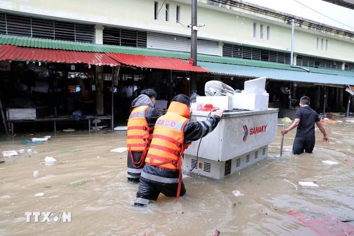 Cán bộ chiến sỹ Công an tỉnh Lạng Sơn giúp tiểu thương di chuyển tài sản ra khỏi khu vực ngập sâu. (Ảnh: Văn Đạt/TTXVN)