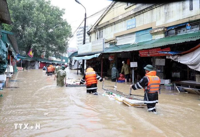 Cán bộ chiến sỹ Công an tỉnh Lạng Sơn giúp tiểu thương di chuyển tài sản ra khỏi khu vực ngập sâu. (Ảnh: Văn Đạt/TTXVN)